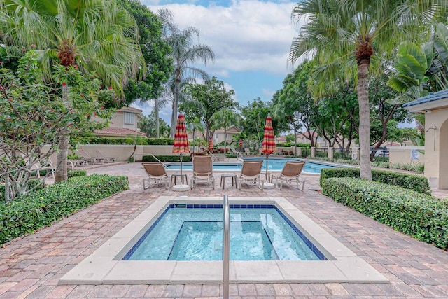 community pool with a patio area, a community hot tub, and fence