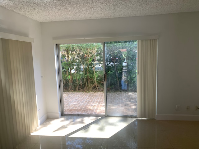 doorway to outside featuring tile patterned floors, a textured ceiling, and baseboards