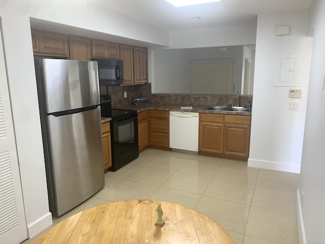 kitchen with light tile patterned flooring, backsplash, black appliances, and a sink