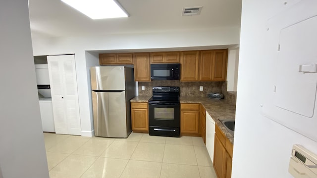 kitchen with brown cabinetry, visible vents, light tile patterned flooring, black appliances, and tasteful backsplash