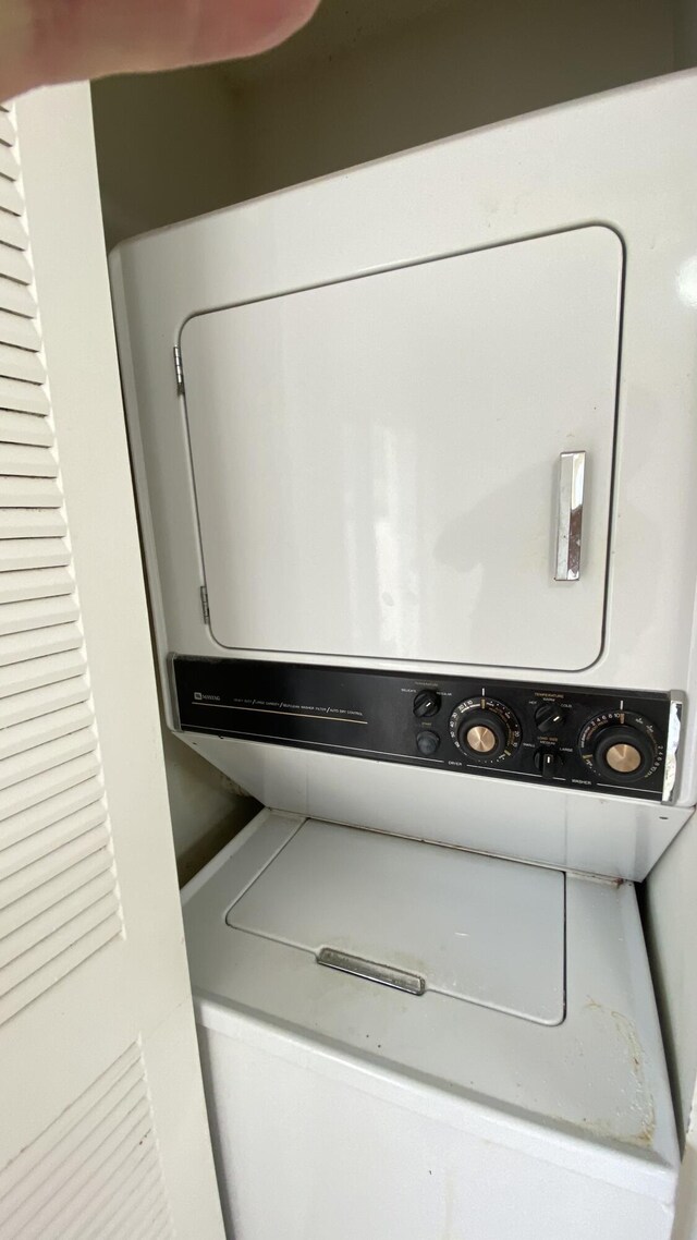 clothes washing area featuring stacked washer and dryer and laundry area