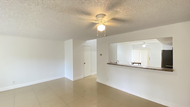 spare room featuring a textured ceiling, baseboards, and ceiling fan