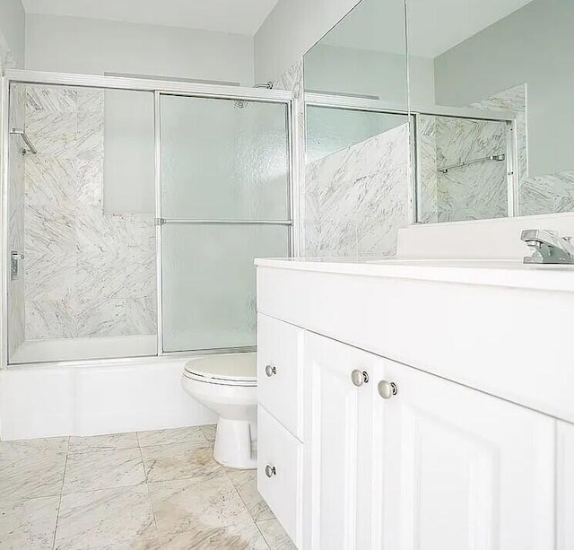 full bathroom featuring vanity, bath / shower combo with glass door, and toilet