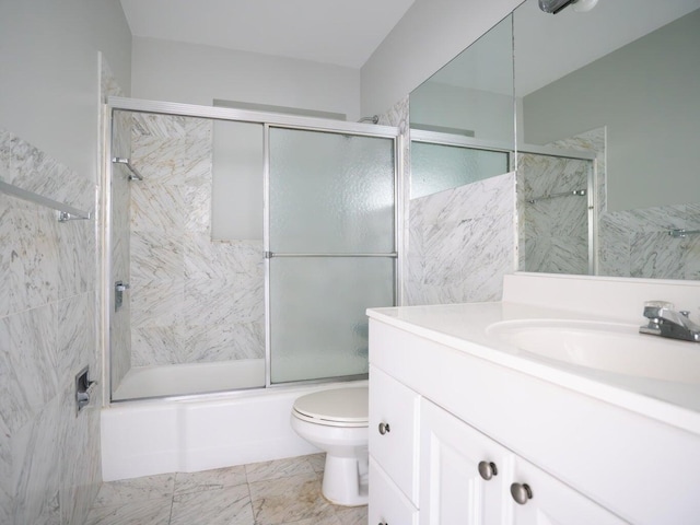 full bathroom with vanity, tile walls, shower / bath combination with glass door, and toilet