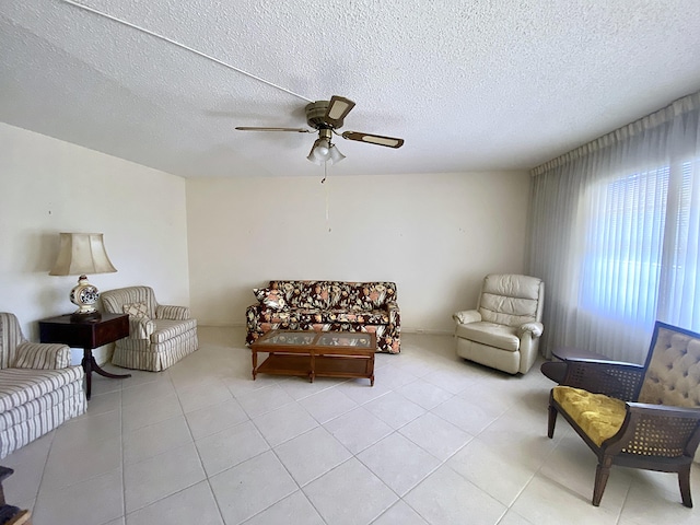 living area with ceiling fan, a textured ceiling, and light tile patterned floors