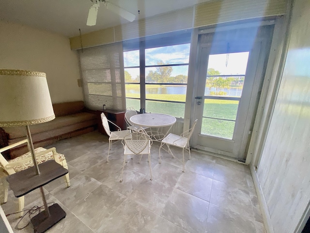 unfurnished sunroom with a water view and ceiling fan