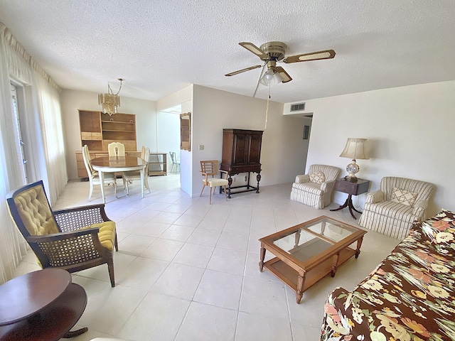 living room featuring light tile patterned floors, ceiling fan with notable chandelier, and a textured ceiling