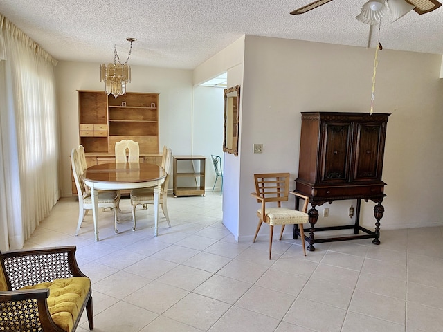 dining area with ceiling fan with notable chandelier, light tile patterned floors, and a textured ceiling