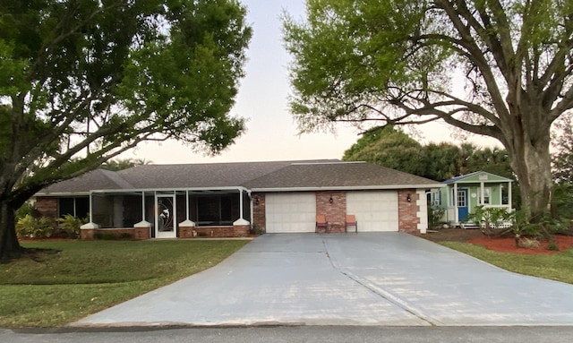 single story home with brick siding, a front lawn, a garage, a sunroom, and driveway