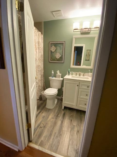 empty room featuring ceiling fan, visible vents, baseboards, and wood finished floors