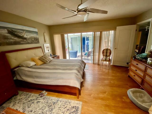 bedroom with light hardwood / wood-style flooring, a textured ceiling, access to outside, and ceiling fan