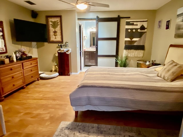 2086 SE Bisbee St, Port Saint Lucie, FL 34952 - bedroom with ceiling fan, a barn door, wood finished floors, ensuite bathroom, and visible vents