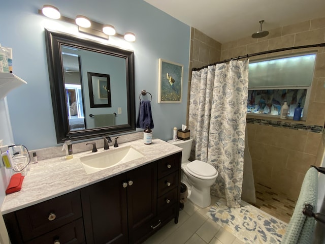 full bath featuring vanity, toilet, tile patterned flooring, and a tile shower