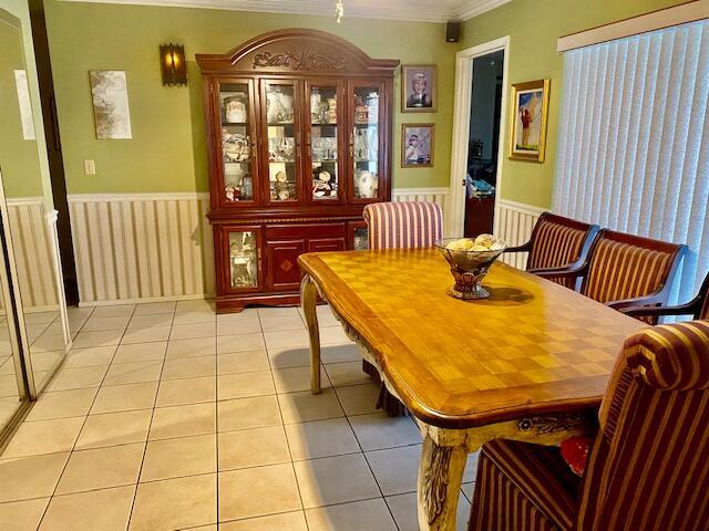 dining room featuring light tile patterned floors, wainscoting, and crown molding