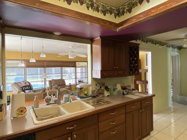 kitchen with a sink, light countertops, light tile patterned flooring, and ceiling fan