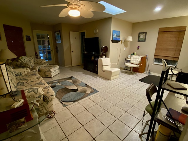 living room featuring light tile patterned floors, ceiling fan, and a skylight