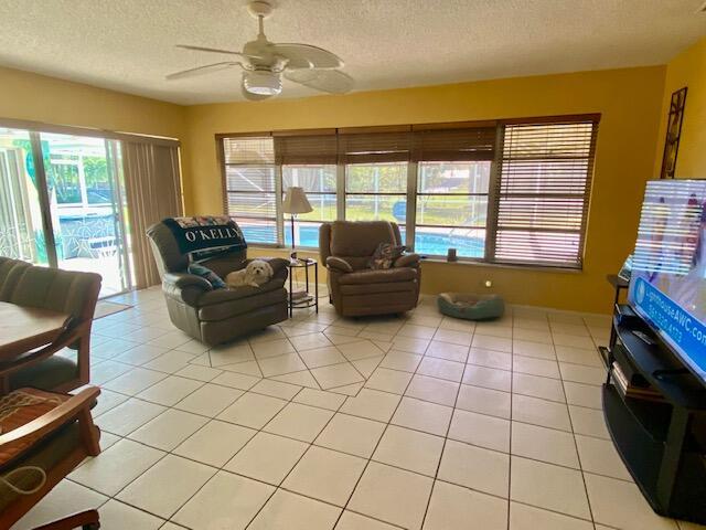 2086 SE Bisbee St, Port Saint Lucie, FL 34952 - living room featuring light tile patterned floors, a textured ceiling, plenty of natural light, and ceiling fan