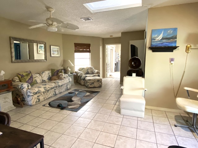 living room featuring light tile patterned floors, visible vents, a skylight, and ceiling fan