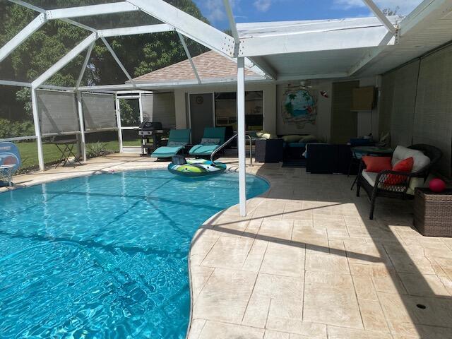 view of swimming pool featuring area for grilling, outdoor lounge area, glass enclosure, and a patio