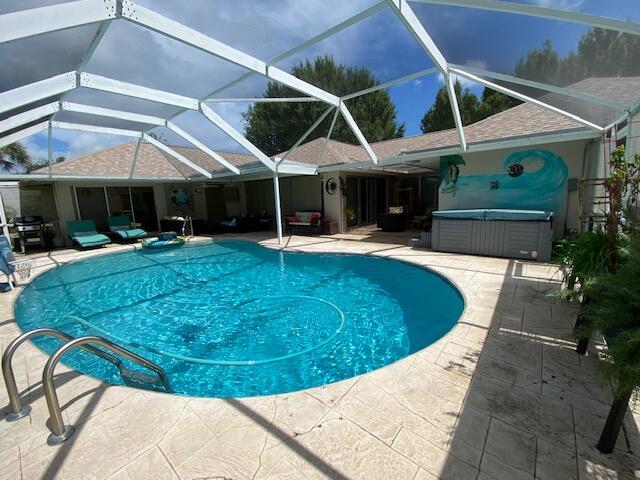 view of swimming pool featuring a hot tub, a lanai, and a patio area