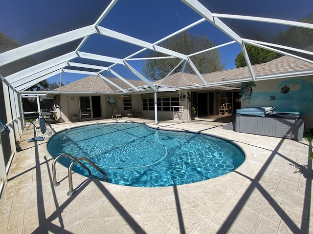 pool featuring glass enclosure, a patio, and a hot tub