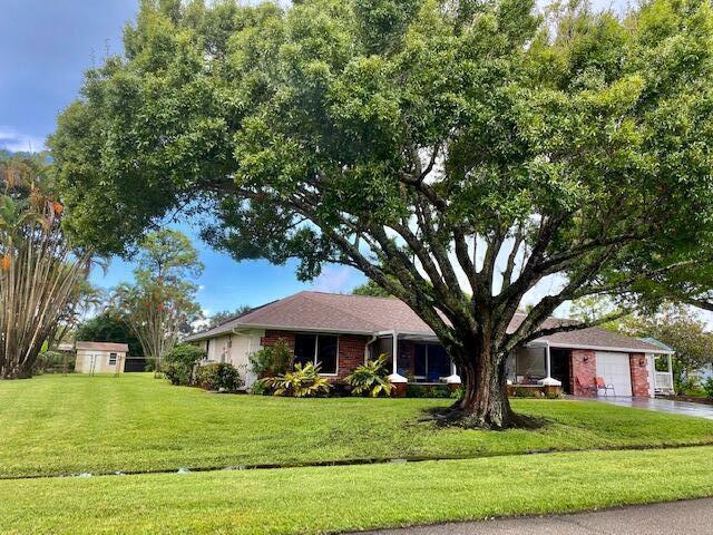 2086 SE Bisbee St, Port Saint Lucie, FL 34952 - single story home featuring a storage unit, a garage, a front lawn, and driveway