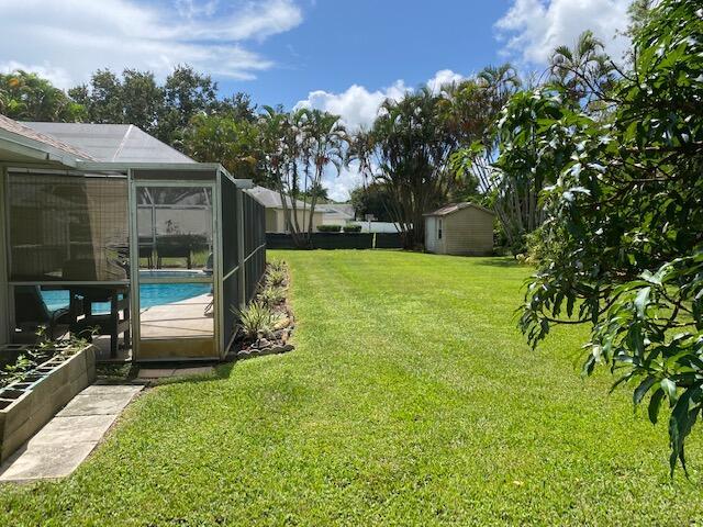 view of yard featuring a lanai and a storage unit