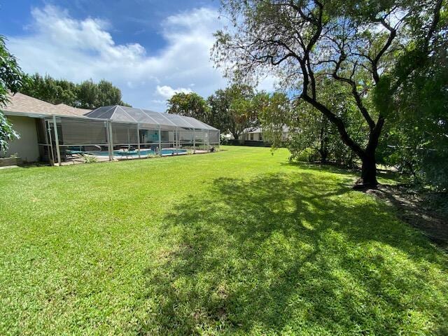 2086 SE Bisbee St, Port Saint Lucie, FL 34952 - view of yard with glass enclosure and an outdoor pool