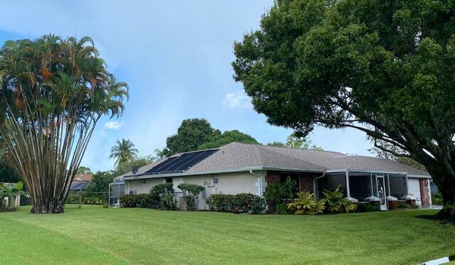 view of side of property with a lawn and solar panels