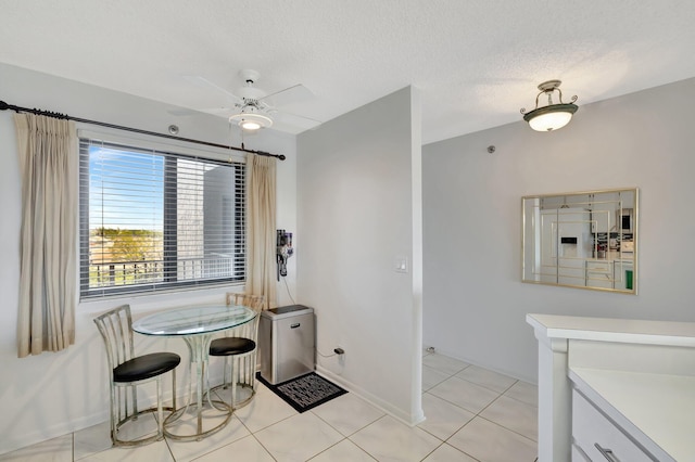 dining space with ceiling fan, a textured ceiling, and light tile patterned floors