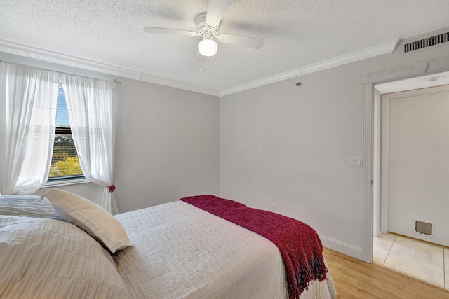 bedroom featuring ornamental molding, a textured ceiling, and light hardwood / wood-style flooring