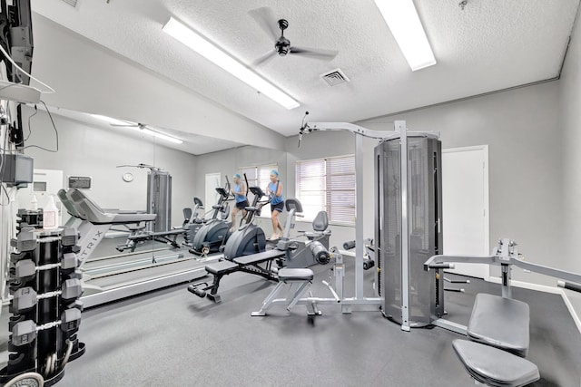 exercise room featuring ceiling fan, lofted ceiling, and a textured ceiling