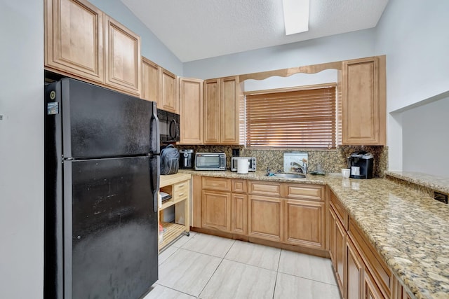 kitchen with tasteful backsplash, lofted ceiling, sink, light stone counters, and black appliances