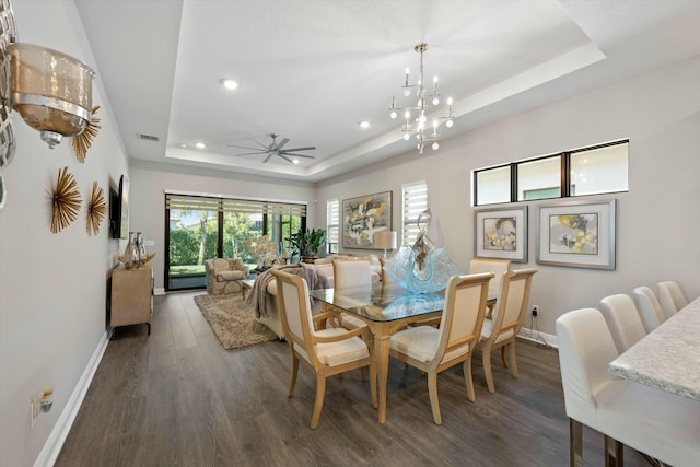 dining space featuring a tray ceiling, dark hardwood / wood-style flooring, and ceiling fan with notable chandelier