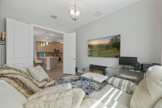 living room with an inviting chandelier, hardwood / wood-style floors, and sink