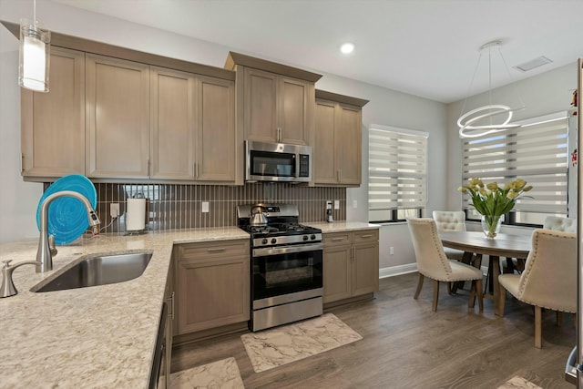 kitchen featuring appliances with stainless steel finishes, decorative light fixtures, sink, and decorative backsplash