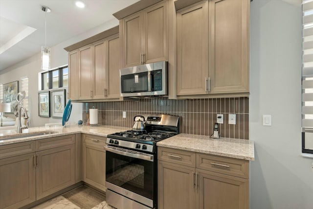 kitchen with appliances with stainless steel finishes, hanging light fixtures, sink, and decorative backsplash