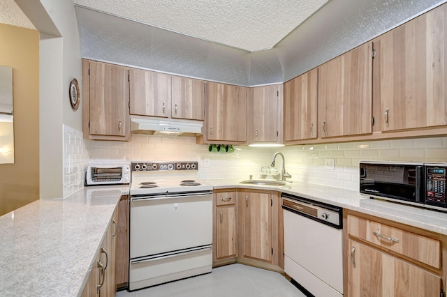 kitchen with under cabinet range hood, decorative backsplash, white appliances, a textured ceiling, and a sink