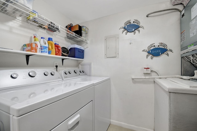 washroom with electric panel, baseboards, laundry area, and washer and clothes dryer