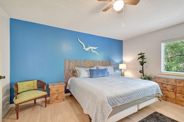 bedroom with ceiling fan, a textured ceiling, and wood finished floors