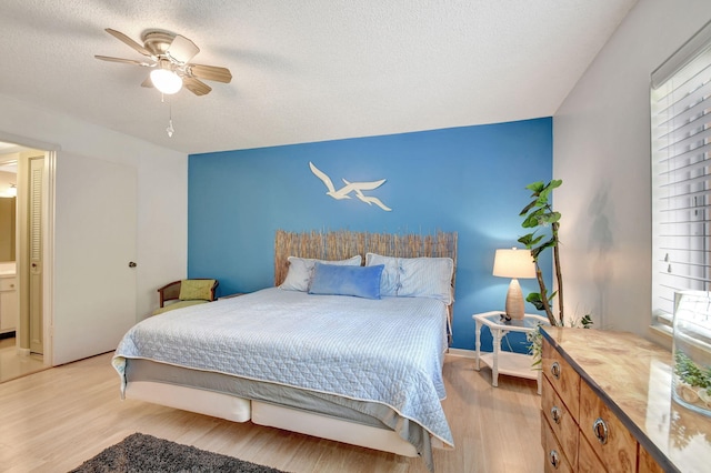 bedroom featuring light wood finished floors, a textured ceiling, and a ceiling fan