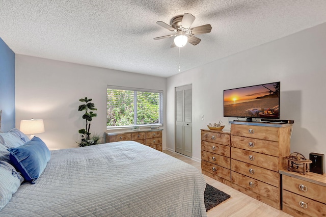 bedroom featuring a ceiling fan, wood finished floors, a closet, and a textured ceiling