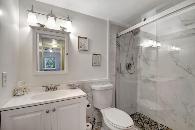 bathroom featuring a wainscoted wall, toilet, a marble finish shower, tile walls, and vanity