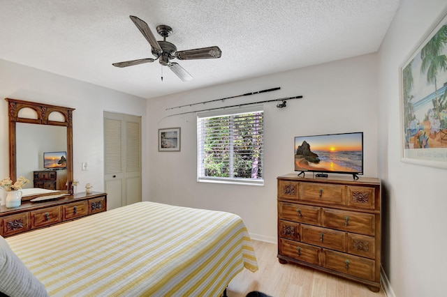 bedroom with a ceiling fan, a textured ceiling, wood finished floors, a closet, and baseboards