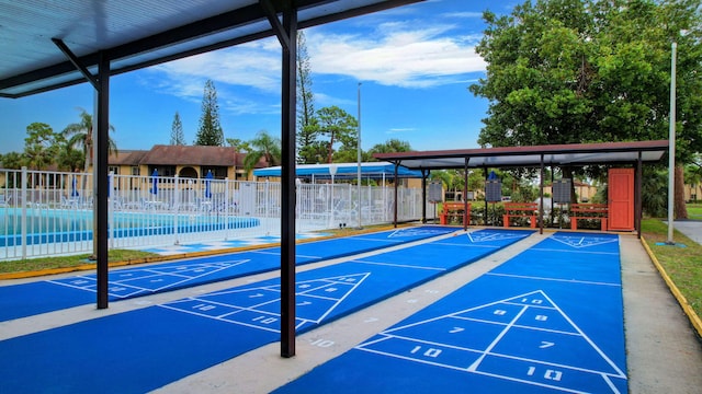 view of property's community featuring shuffleboard and fence