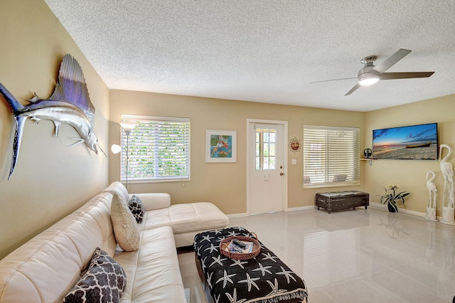 tiled living room featuring ceiling fan, baseboards, and a textured ceiling