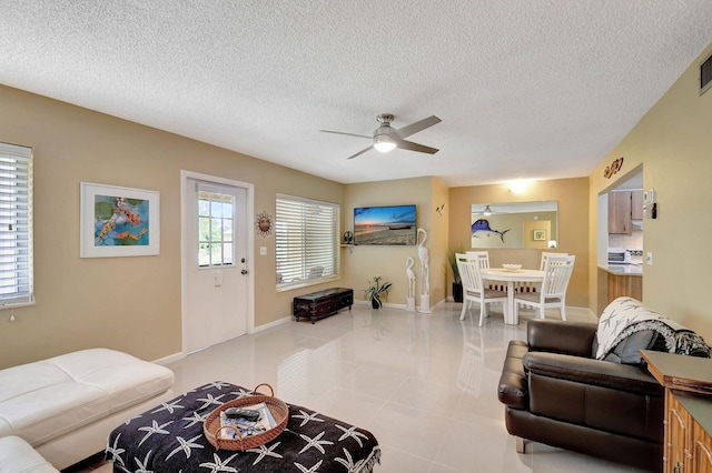 tiled living area with a textured ceiling, baseboards, and ceiling fan