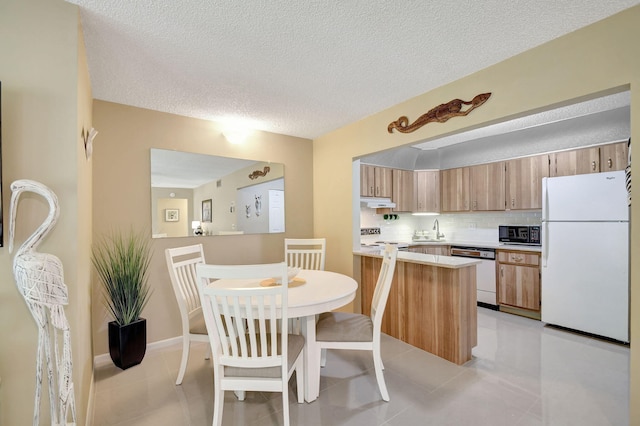 kitchen with a sink, backsplash, white appliances, light countertops, and light tile patterned floors