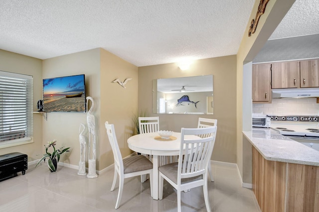 dining area with light tile patterned floors, ceiling fan, a textured ceiling, and baseboards