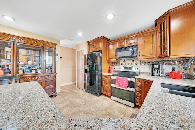 kitchen featuring sink, light tile patterned floors, tasteful backsplash, black appliances, and light stone countertops